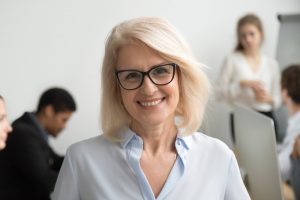 Smiling senior businesswoman wearing glasses portrait with busin